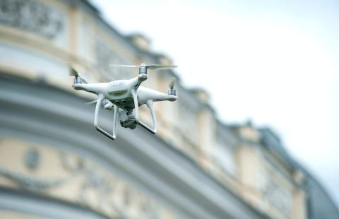 White drone flying in front of a building