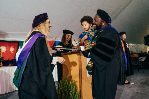 Student holding child while receiving degree